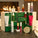 12 Days of Tropic – Advent Calendar. A luxury green festive calendar with twelve drawers, displayed open in front of a fireplace, showcasing a variety of Tropic skincare and body care products including cleansers, serums, mists, creams, and lip treatments.